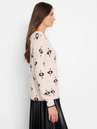 Cream knit sweater with black scattered geometric shapes. Ribbed cuffs and hem feature black trim.