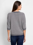 Black & white tuck stitch sweater with 3/4 sleeves. Features a geometric pattern and striped ribbed cuffs & hem.