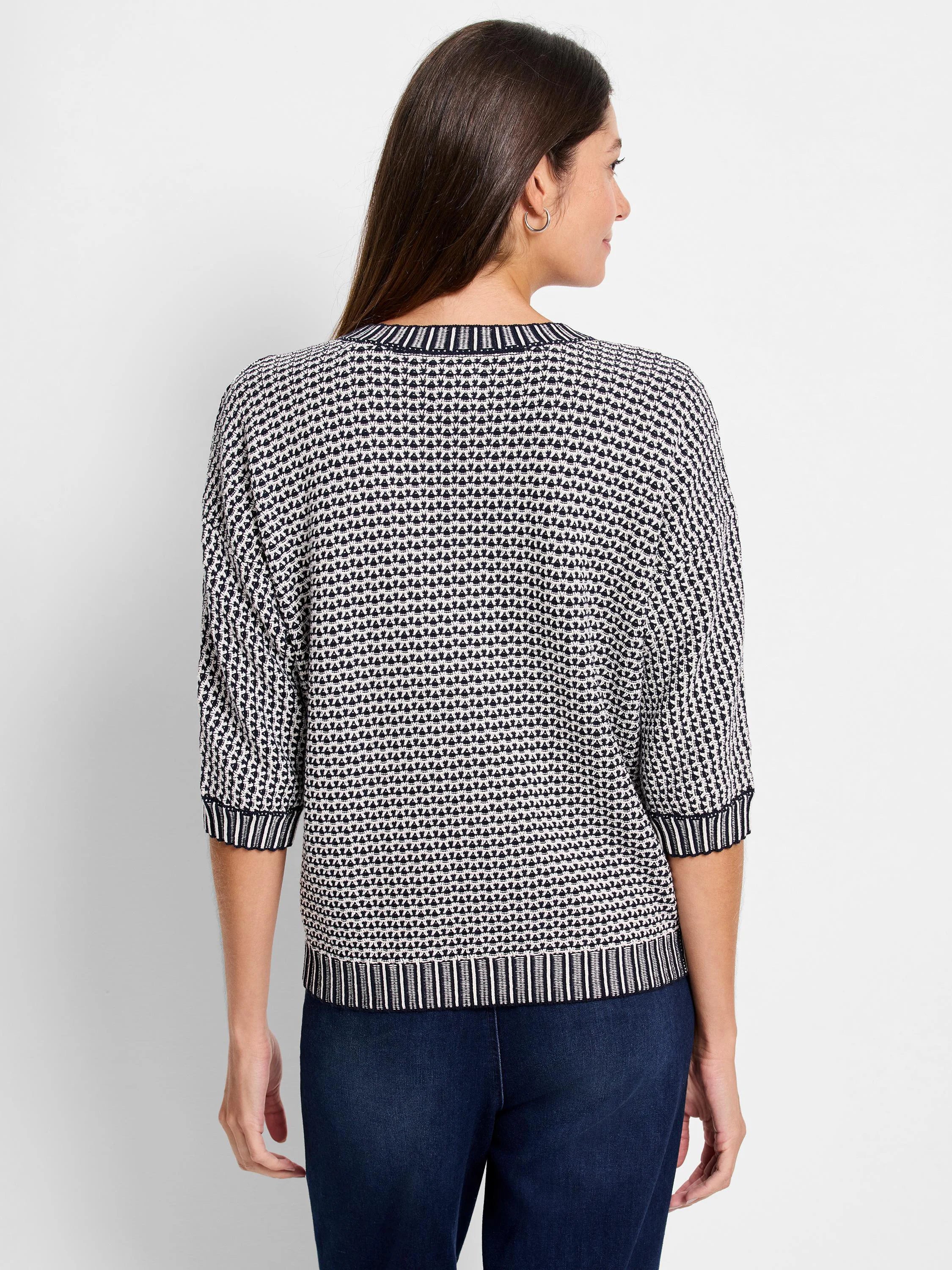 Black & white tuck stitch sweater with 3/4 sleeves. Features a geometric pattern and striped ribbed cuffs & hem.