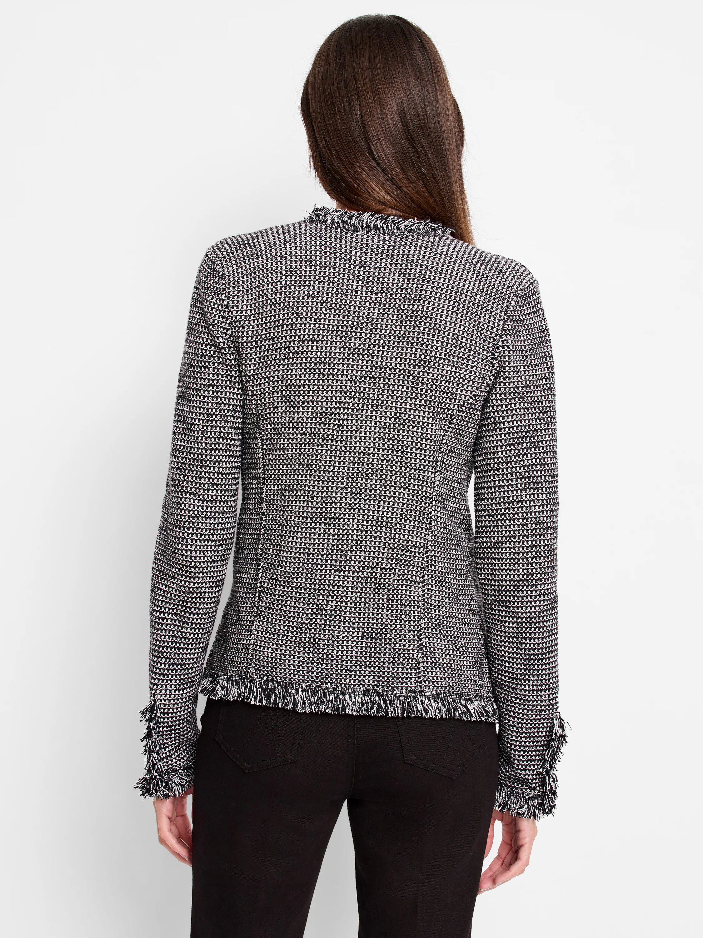 Black and white geometric knit jacket, seen from back. Features fringe along the neckline, hem, and cuffs.