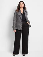 Black and white tweed-knit jacket with fringe along lapels, front opening, and cuffs.