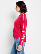 Bright pink sweater with white decorative stitched bands on the sleeves.