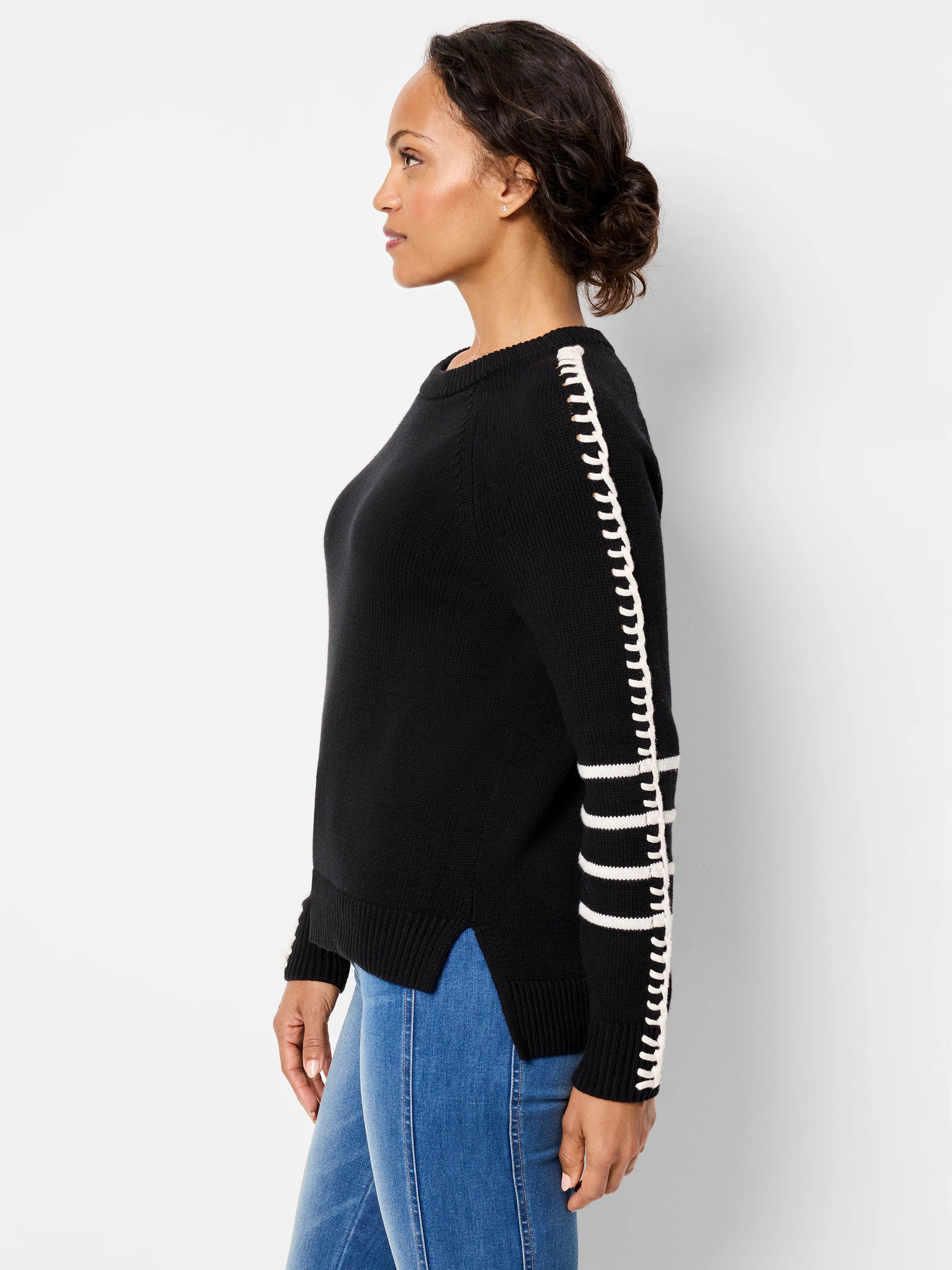 Black sweater with white dash-stitch detail along outer sleeves and three white stripes near cuffs.