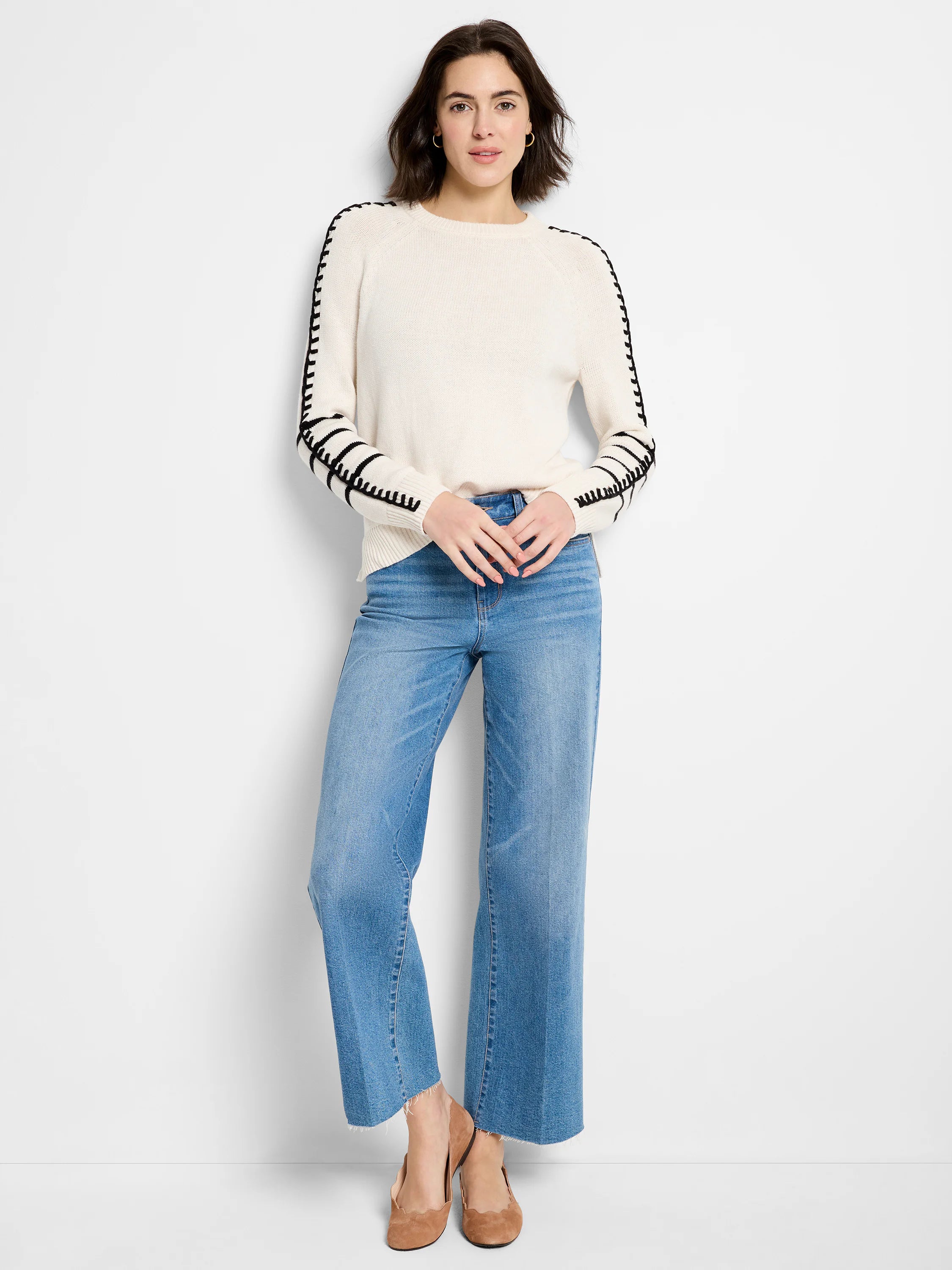 Off-white sweater with black dashed stitching on raglan seams and cuffs.