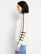 Cream sweater with black wavy stripe down arm and two black horizontal stripes above cuff.