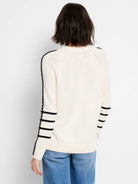 Off-white crewneck sweater with black braided stripe on outer arms and three black horizontal bands on forearms.