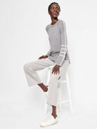 Grey knit sweater with white ladder-stitch stripes on sleeves.