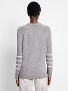 Back of a grey crew neck sweater with white triple stripes on both sleeves.
