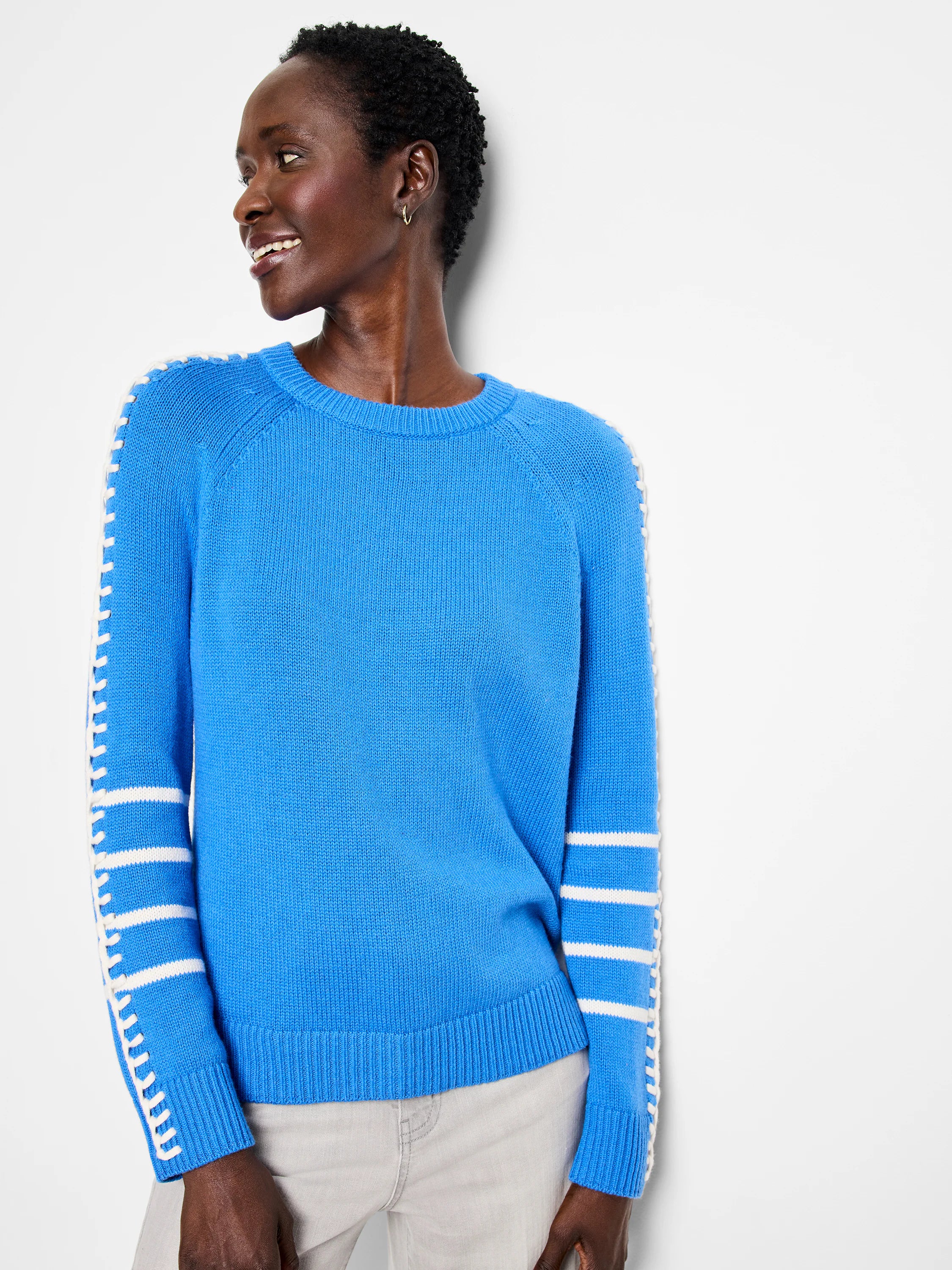 Bright blue sweater with white horizontal stripes on lower sleeves and white lacing along outer sleeve seams. Ribbed...