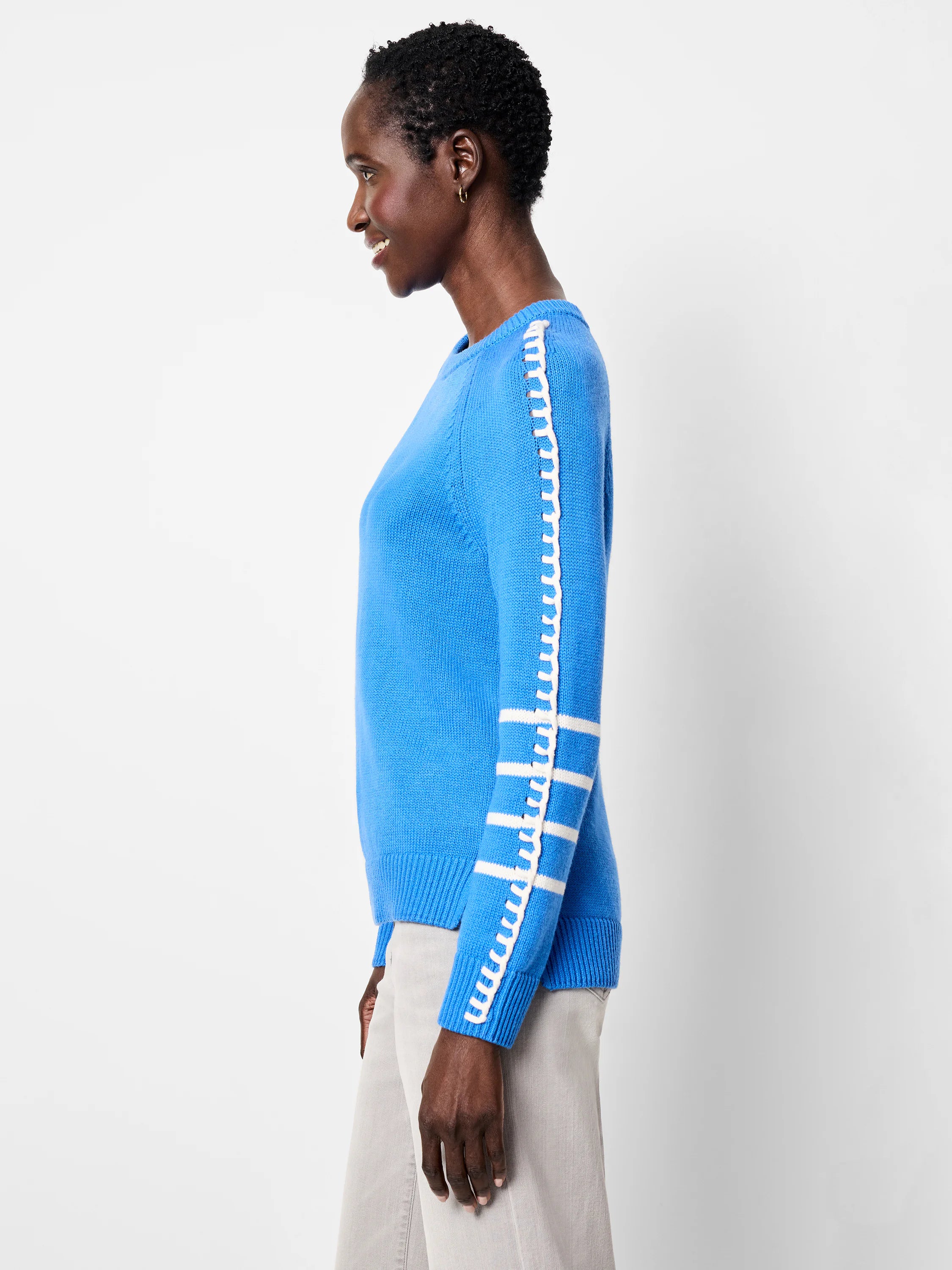 Blue sweater with white decorative lacing along the outer sleeve seam and three white stripes on the lower sleeve.