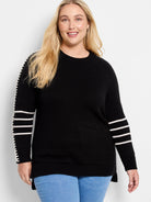 Black sweater with white horizontal stripes on both sleeves. White stitch detailing follows the raglan seams.