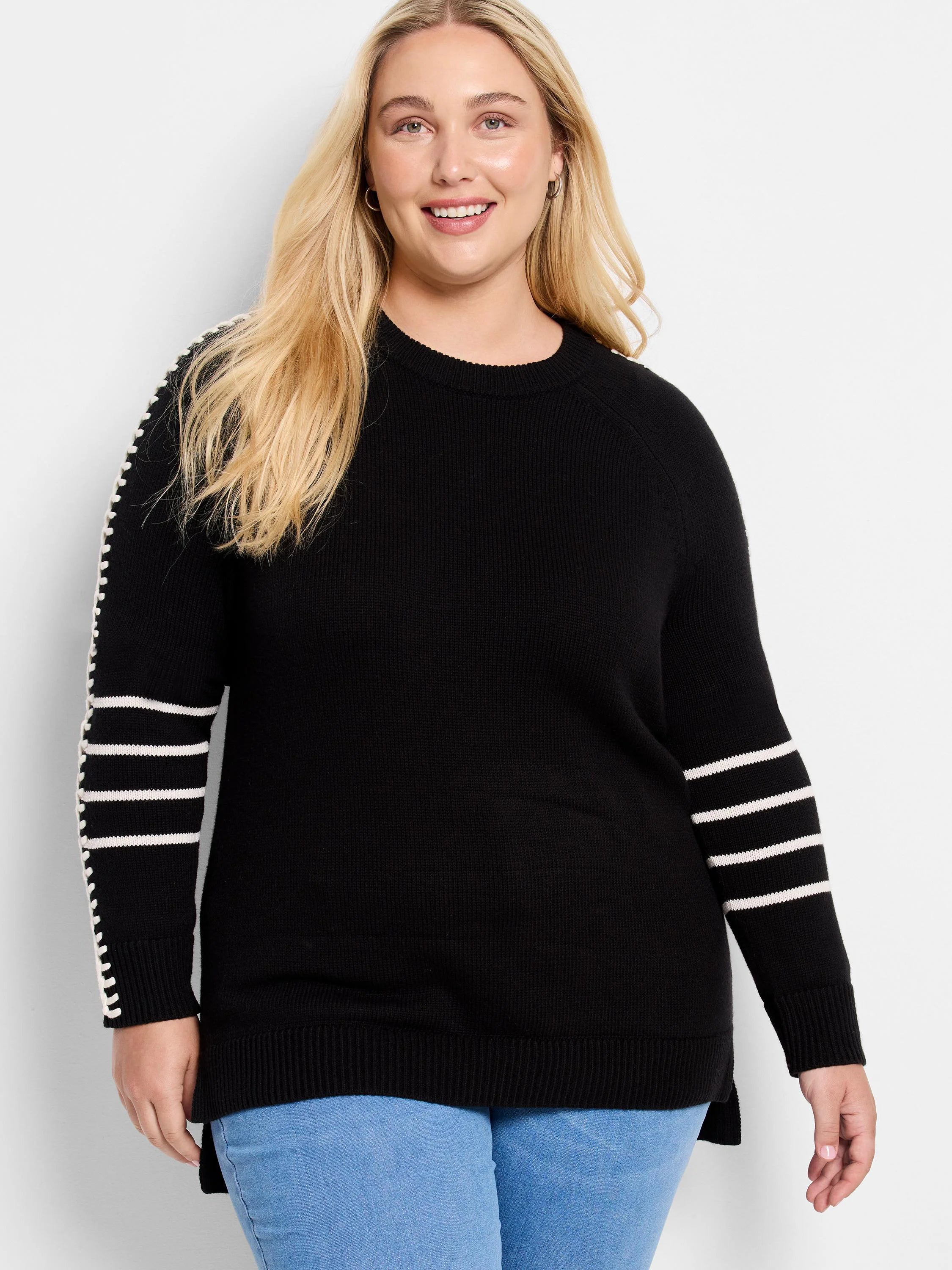 Black sweater with white horizontal stripes on both sleeves. White stitch detailing follows the raglan seams.