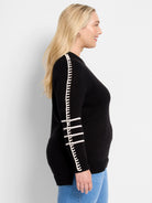 Black sweater with a white decorative vertical stripe on the outer arm, and three horizontal white stripes on the lower...