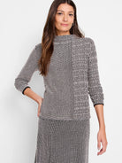 Black and blush pink patterned knit sweater. Mock neck, three-quarter sleeves, and a textured design.