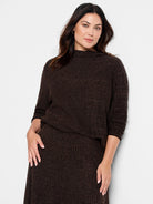 Brown sweater with subtle darker brown textured pattern. Mock neck, three-quarter sleeves.