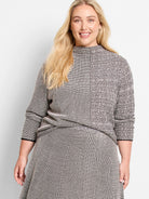Black and off-white pixelated knit sweater; mock neck, three-quarter sleeves, and a textured pattern.