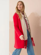 Reversible jacket; one side red, the other cream.  Features long fringe in red.