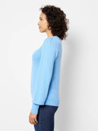 Light blue sweater with round neck, subtle puffed sleeves, and ribbed cuffs/hem.