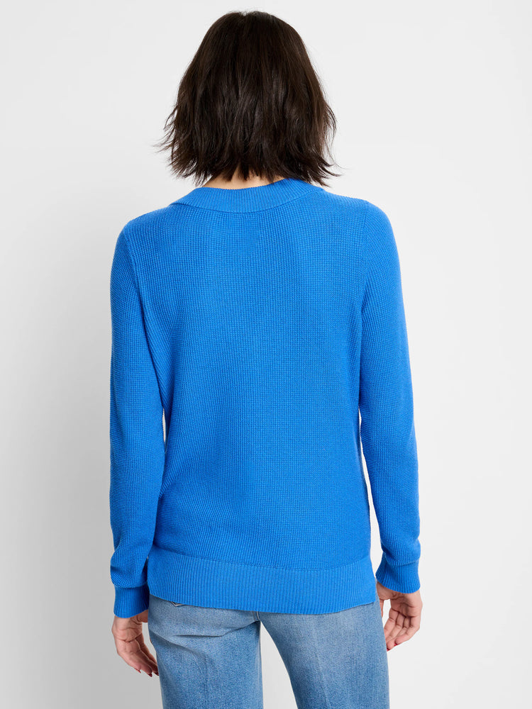 Back of a bright blue waffle-knit sweater with ribbed details on the neck, cuffs, and hem.