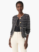 Black and white tweed jacket with gold buttons, elbow-length sleeves, and a patch pocket.