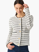 Off-white sweater jacket with black grid pattern, black trim, and gold buttons.