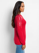 Red sweater with long sleeves and vertical lines of iridescent sequins on the shoulders.