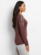 Brown knit sweater with vertical lines of light-colored sequins on one sleeve.