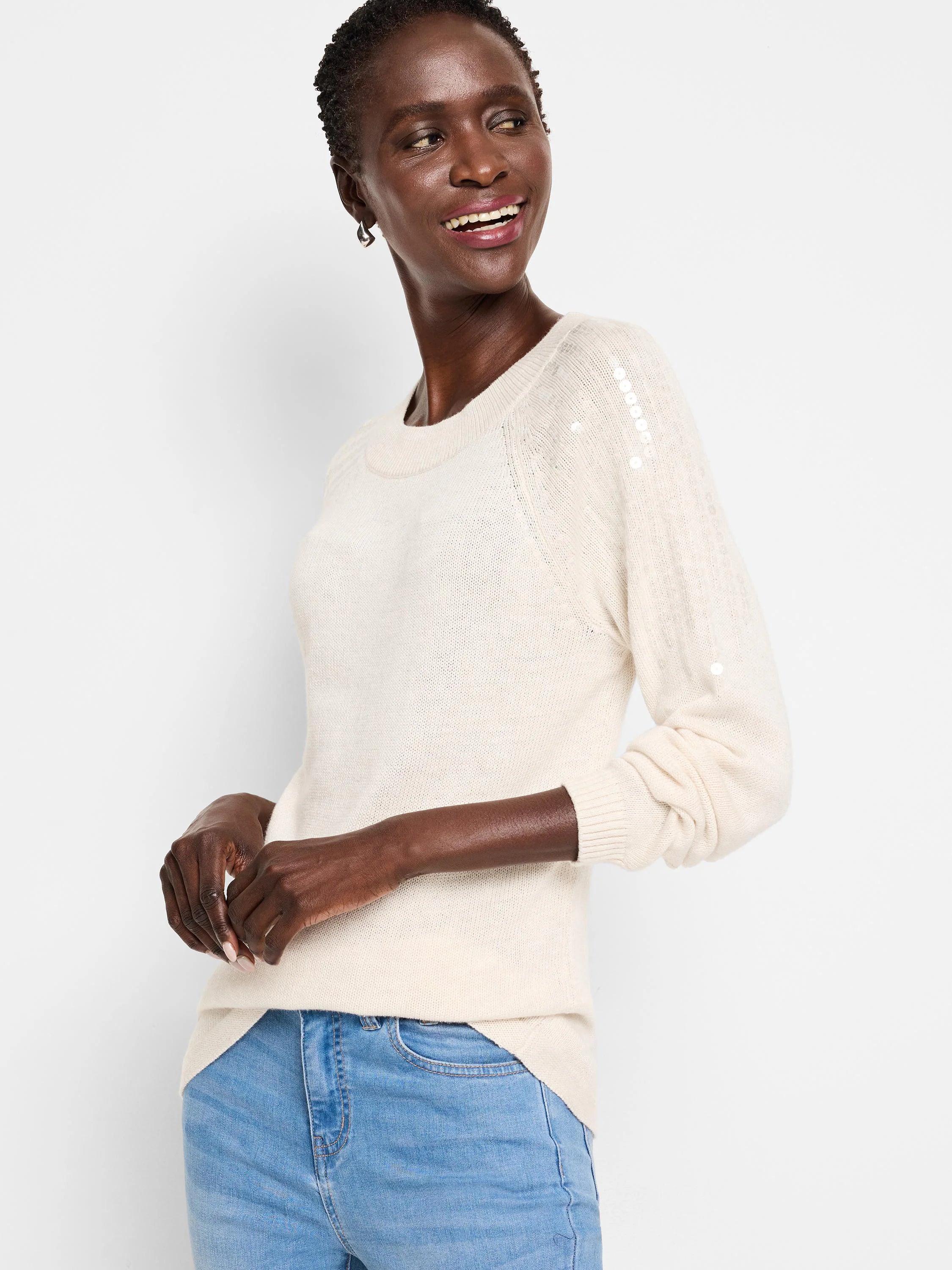 Off-white crewneck sweater with long sleeves and small, light-colored sequins on one shoulder.