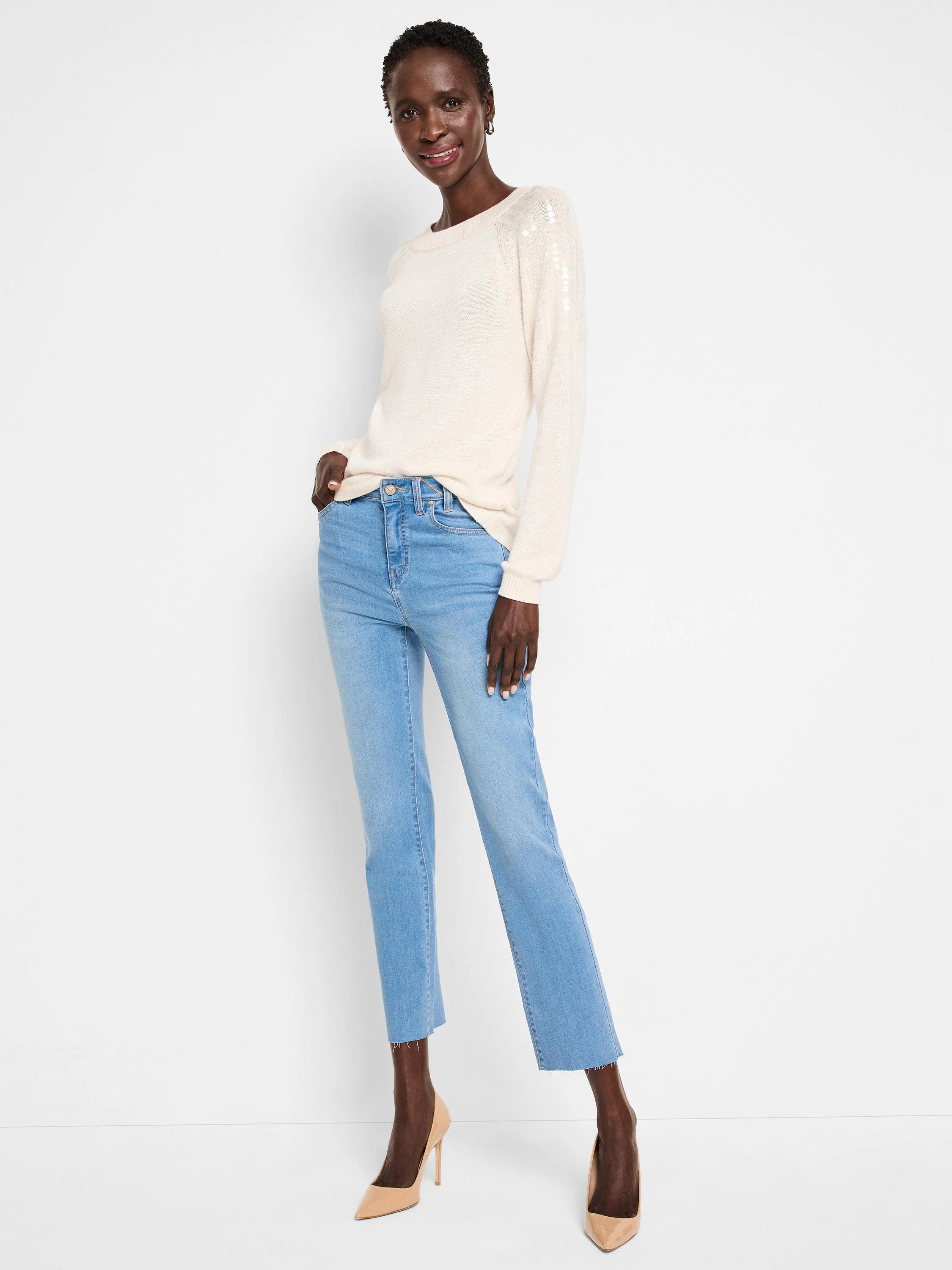 Off-white sweater with light-grey sequins on shoulders.  Long sleeves. Model also wears light-blue jeans and nude heels.