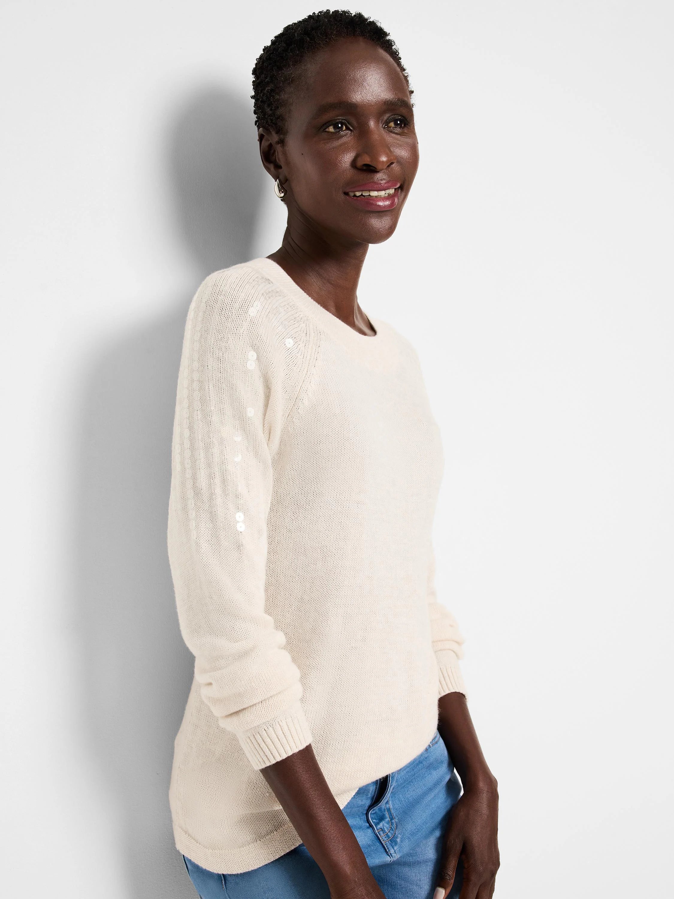 Off-white crewneck sweater with subtle, light-colored sequins on the upper sleeves.
