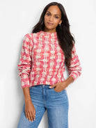 Pink and cream waffle-knit sweater with a mock neck and long sleeves.  A textured, plaid-like pattern.