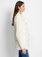 Off-white quilted puffer jacket with off-white knit sleeves and dark buttons. Side view.
