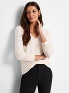 Cream knit V-neck sweater with ribbed trim along the neckline and cuffs.