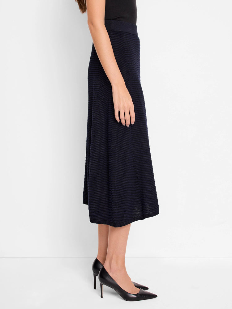 Model wears a dark blue pixel knit A-line midi skirt, falling below the knee.
