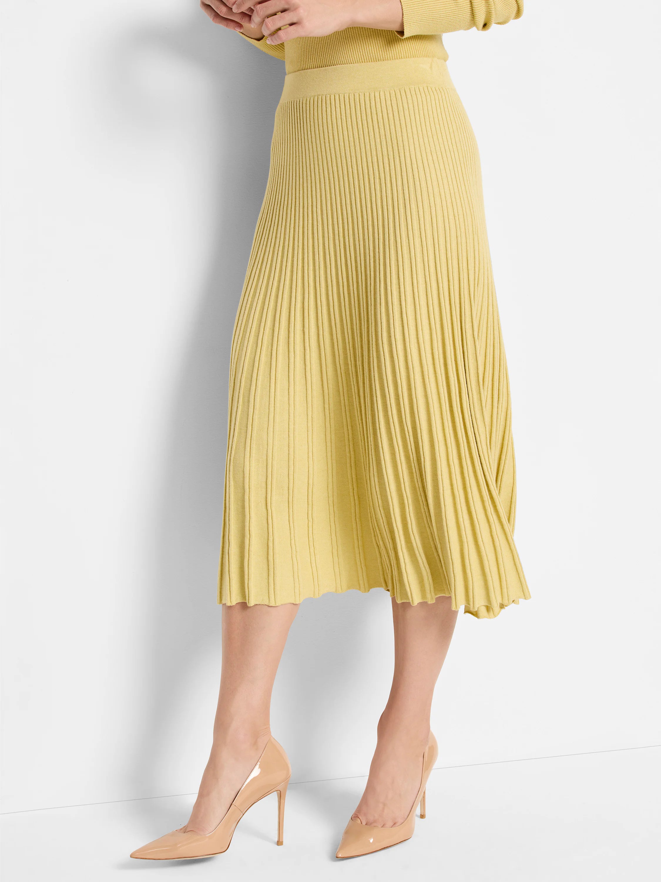 Pale yellow ribbed sweater skirt, midi-length, with a subtle scalloped hem.
