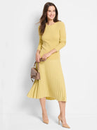 Pastel yellow ribbed knit midi skirt with flowing vertical pleats.