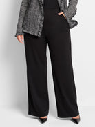 Black wide-leg pants; high waist; model also wears a black and white patterned jacket.