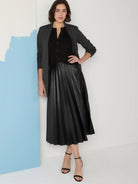Black faux leather midi skirt with pleats.  Model wears it with a black top and gray jacket.