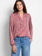 Red, cream, and black herringbone patterned long-sleeve blouse with a v-neck.