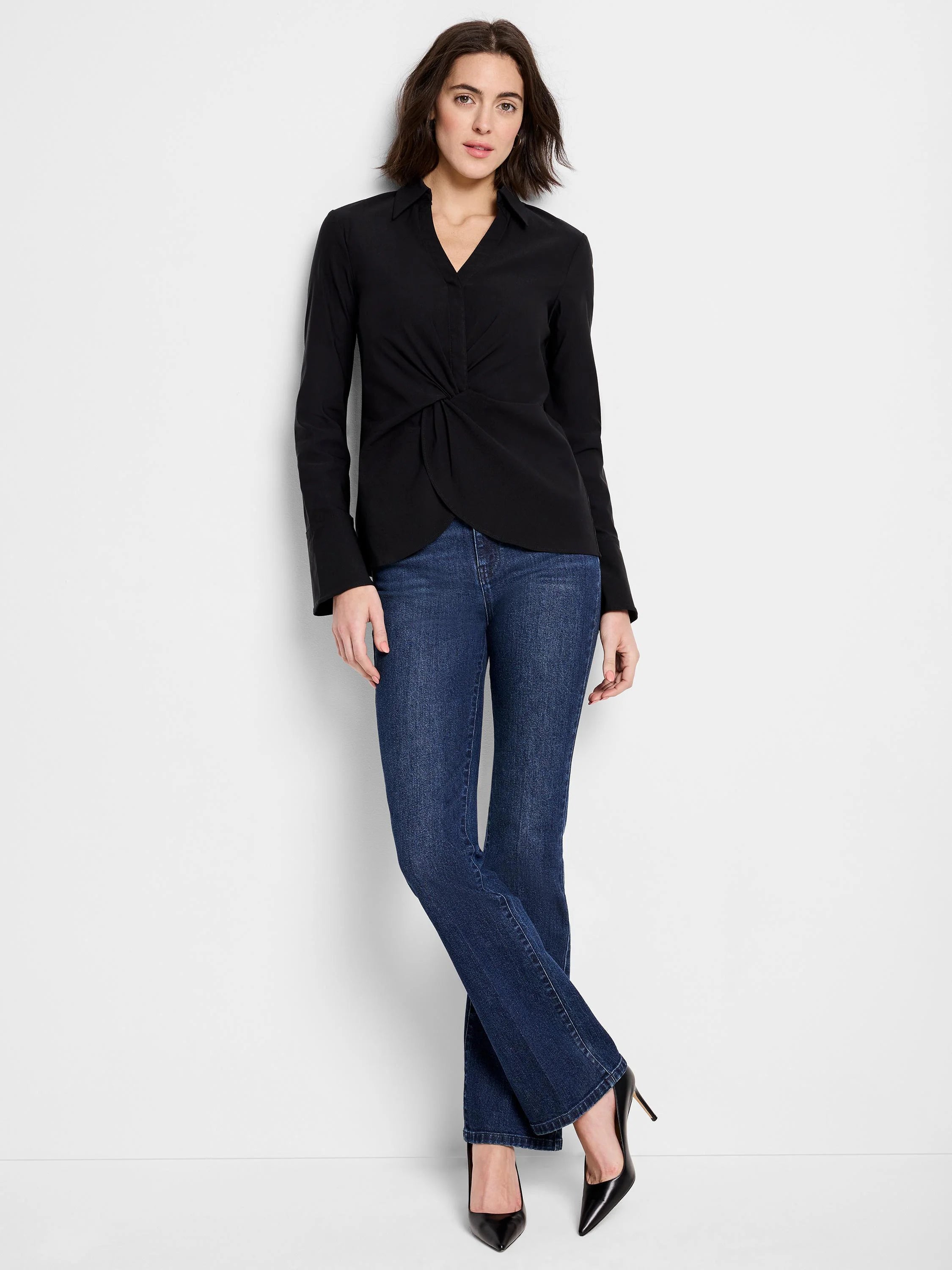 Black long-sleeve shirt, twist front detail.  Solid color. Model also wears blue jeans and black heels.