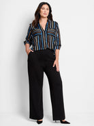 Black wide-leg pants;  striped shirt with blue, brown, beige stripes on black background.