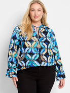 Long-sleeve blouse with keyhole neckline and double ruffled cuffs.  Blue, teal, and beige abstract print on black background.