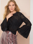 Black lace top with bell sleeves and repeating floral pattern.  Round neckline.