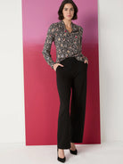 Black top with multicolored spotted pattern on a black background. Long sleeves, collared.