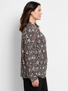 Black top with beige, blue, and red spotted pattern.  Long sleeves, collared.
