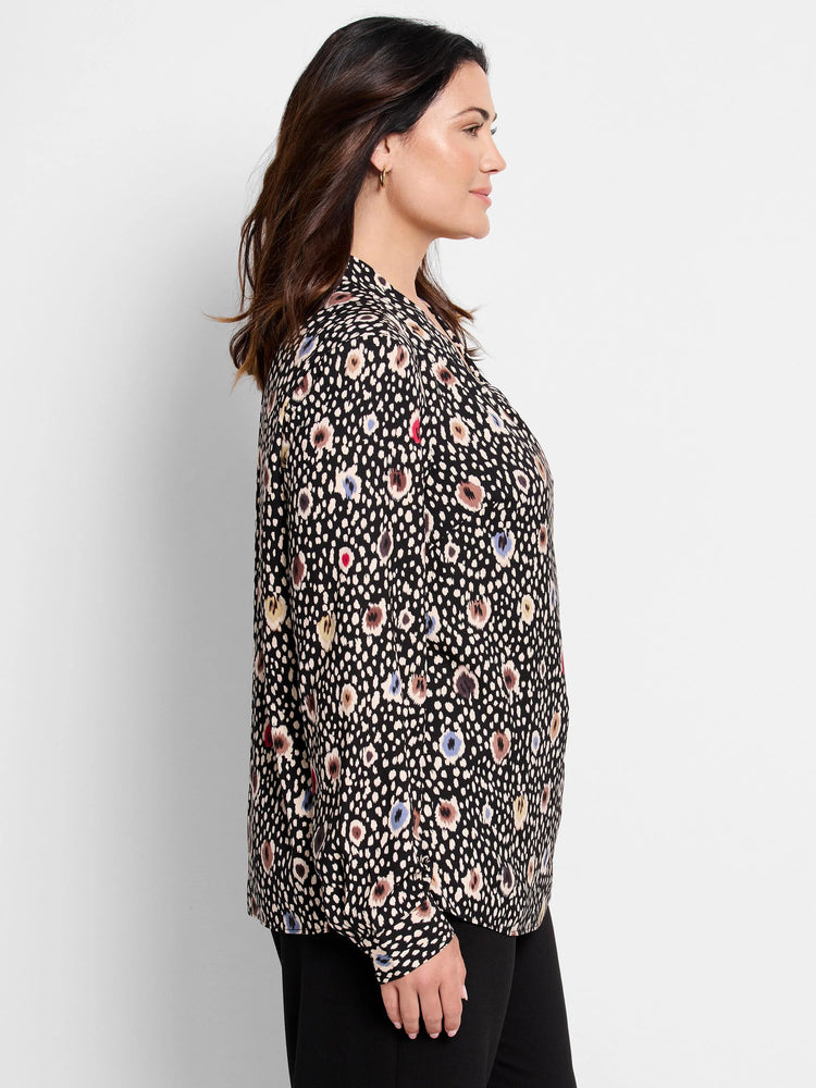Black top with beige, blue, and red spotted pattern.  Long sleeves, collared.