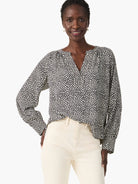 Off-white long-sleeve blouse with dark-blue polka dots, V-neck.
