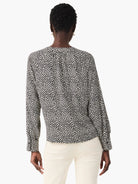 Beige top with dark-brown polka dots, long sleeves, and a V-neck.