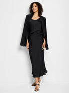 Black crepe midi slip skirt; A-line silhouette, slight flare at hem. Model shown wearing with black top and jacket.