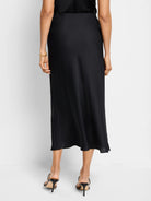 Black midi slip skirt, bias cut, flowing hemline.